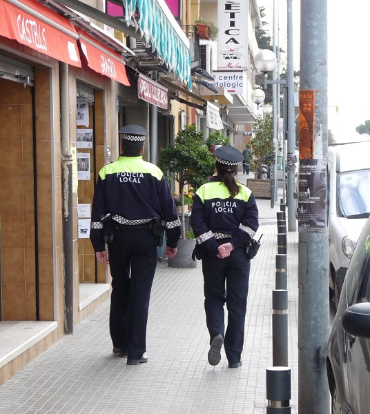 Dos agents de la Policia Local patrullant en una zona comercial