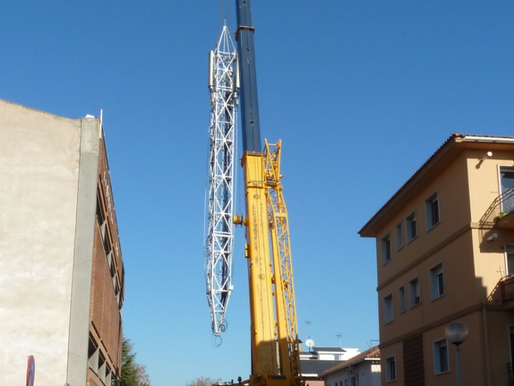 Una grua de grans dimensions fent baixar l'antena a nivell de terra