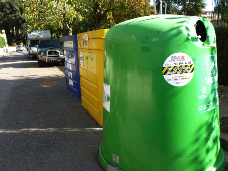 Bateria de contenidors amb avisos sobre la infracció d'abandonar bosses al carrer