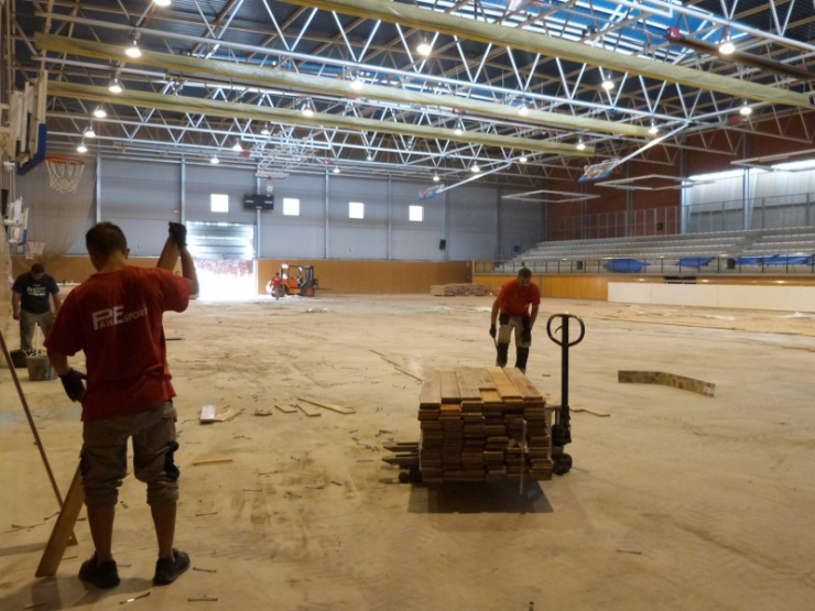 Els operaris treballen reitrant el parquet antic.