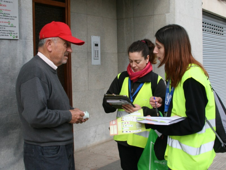 Educadores ambientals enquesten i lliuren bosses compostables a un ciutadà de la vila.